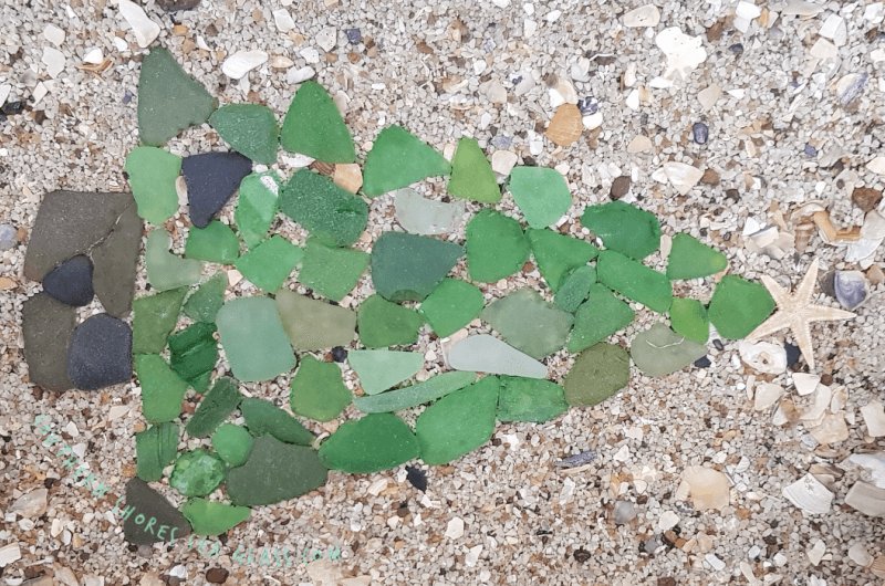 Close up of sea glass Christmas tree mosaic on sand